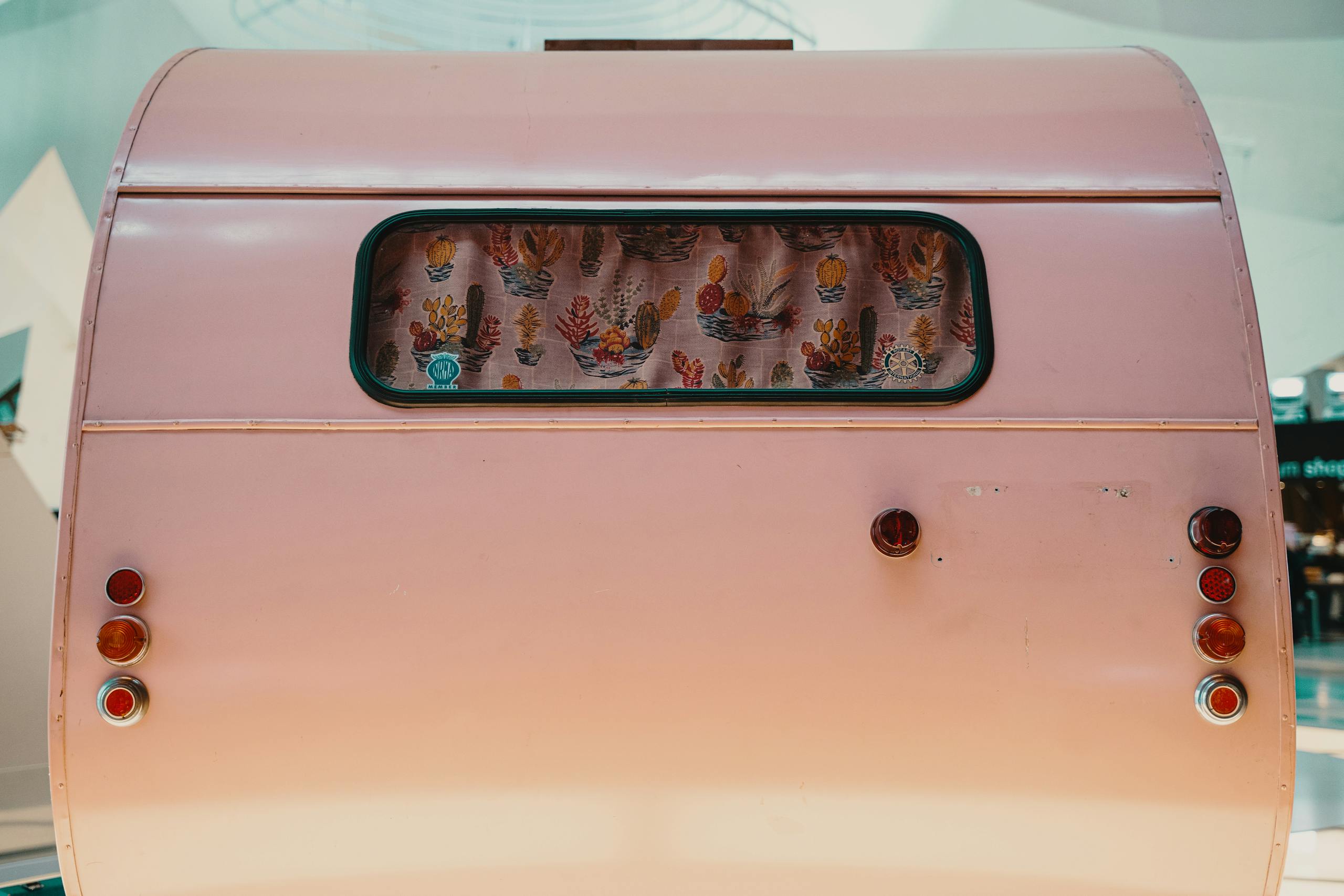 Vintage pink camper with cactus curtain, ideal for travel enthusiasts.