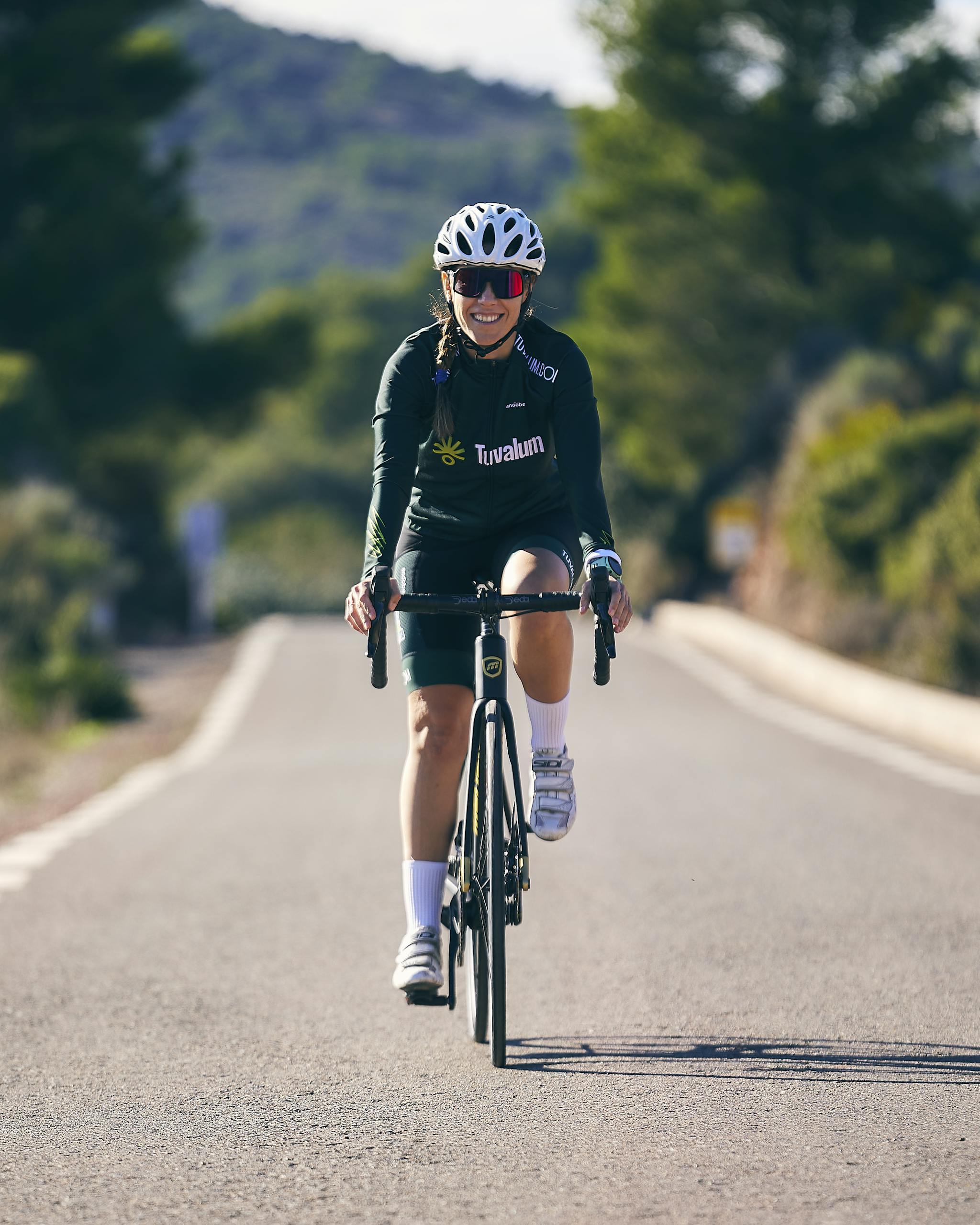 A vibrant image of a woman cycling on a sunny road, embodying active outdoor lifestyle.