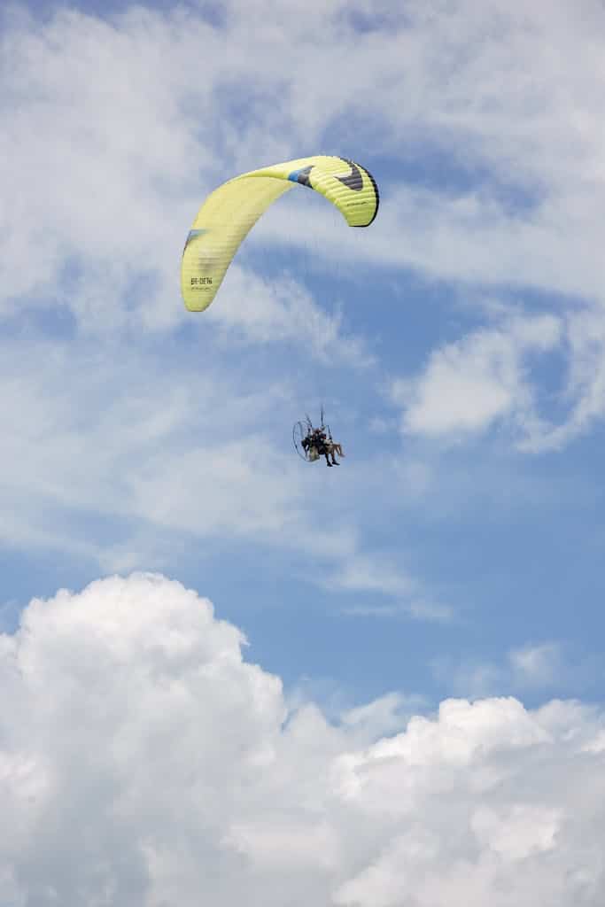 Thrilling paramotoring flight against a scenic blue sky with clouds.